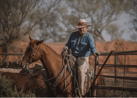 Image of man on horseback closing a gate