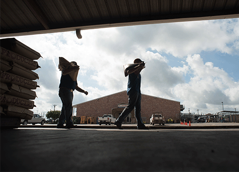 Image of two men walking carrying feed bags